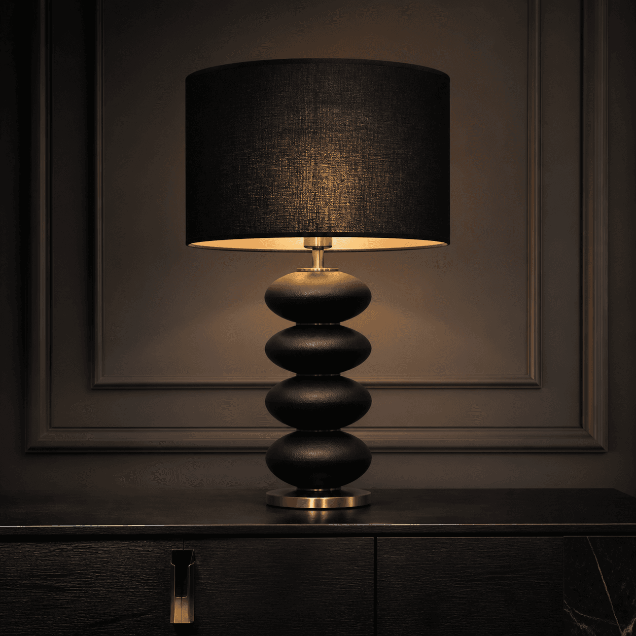 Zwarte tafellamp met warm licht op een donker dressoir