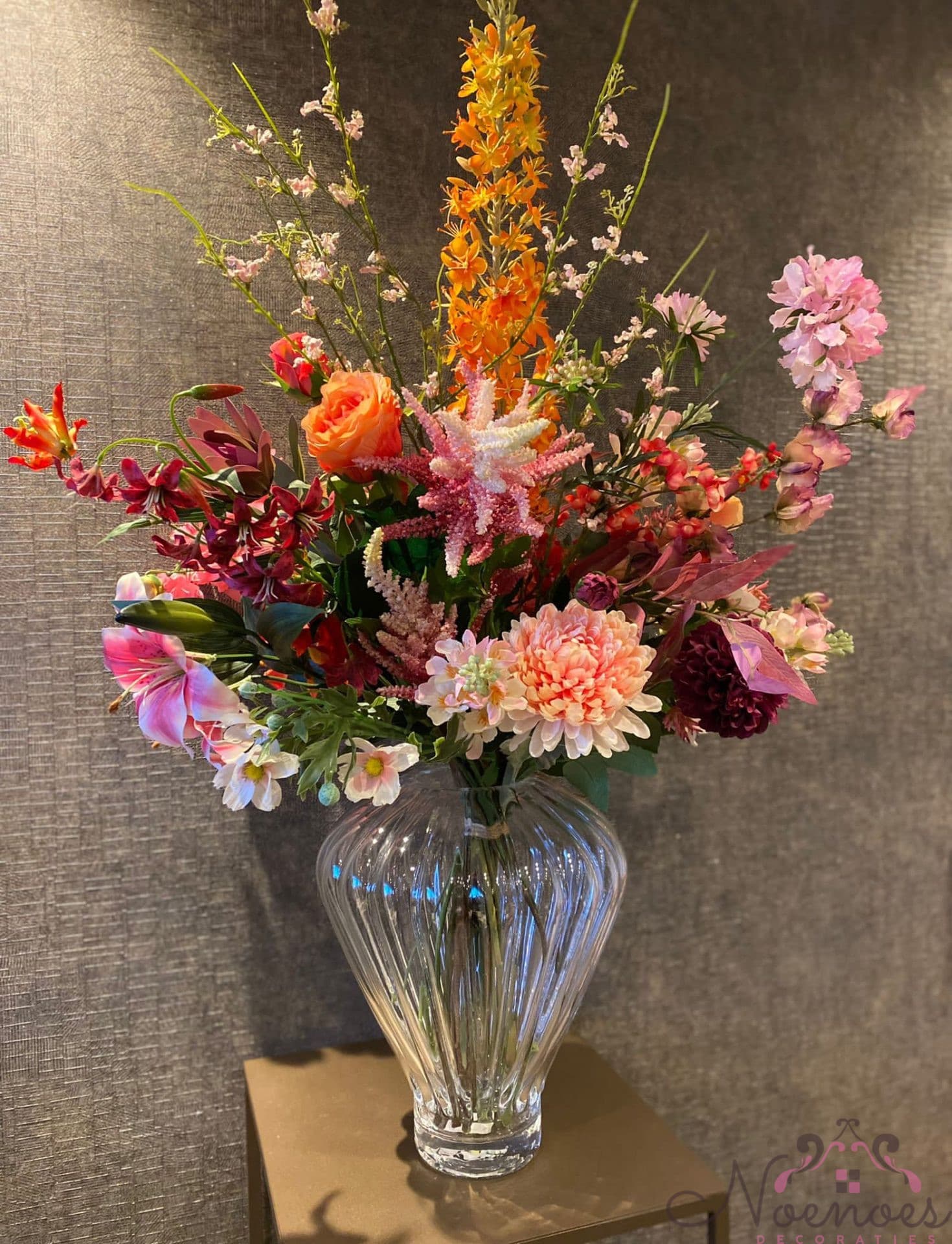Glazen vaas opgemaakt met kleurrijk zijdebloemen boeket