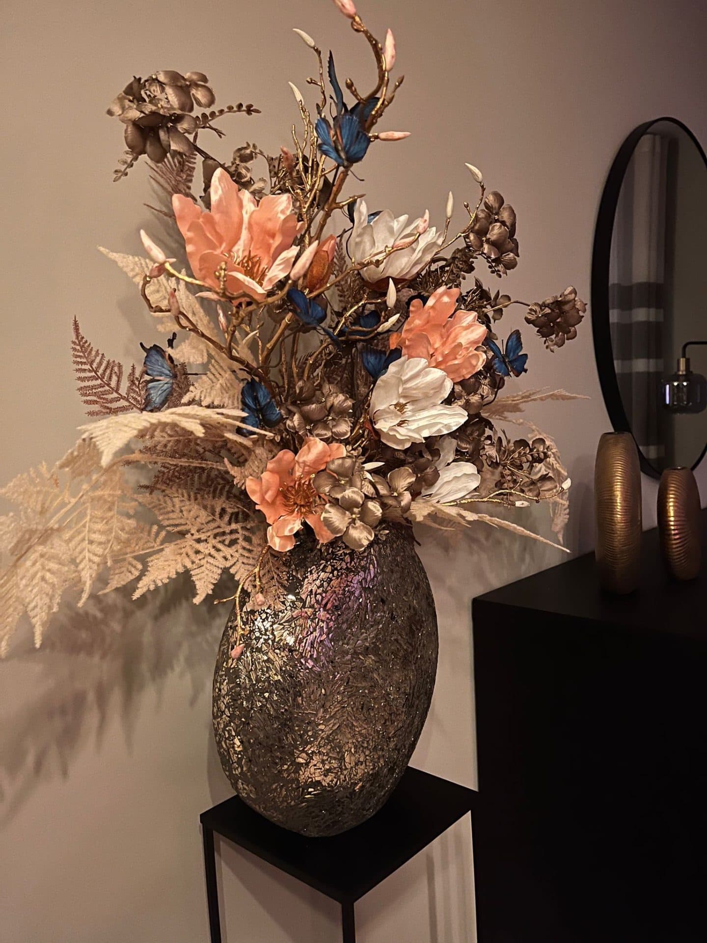 Vaas goud mozaïek opgemaakt met zijdebloemen en blauwe vlinders