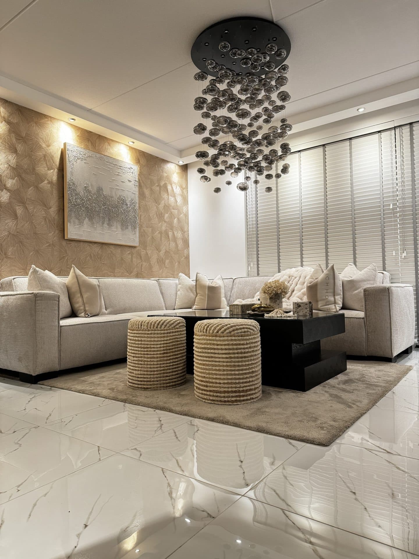 Woonkamerhoek met een crèmekleurige hoekbank, twee ronde gevlochten poefs in naturel voor een zwarte salontafel en een ingelijst kunstwerk aan de wand.