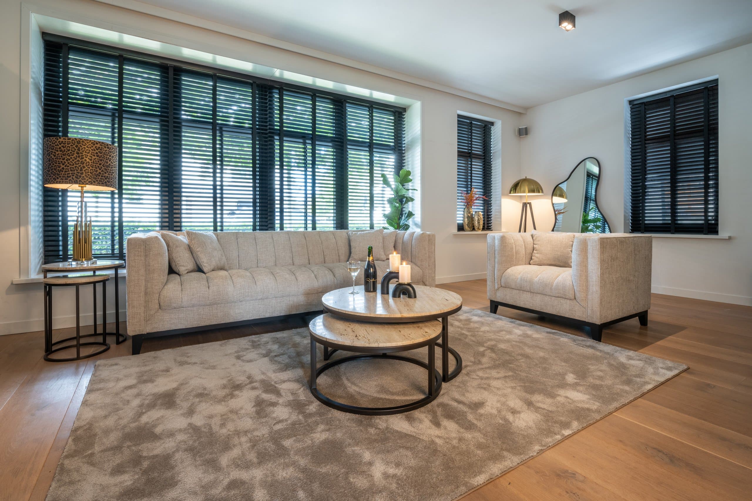 Woonkamer met een brandende tafellamp met luipaardprint op een bijzettafel naast een beige bank