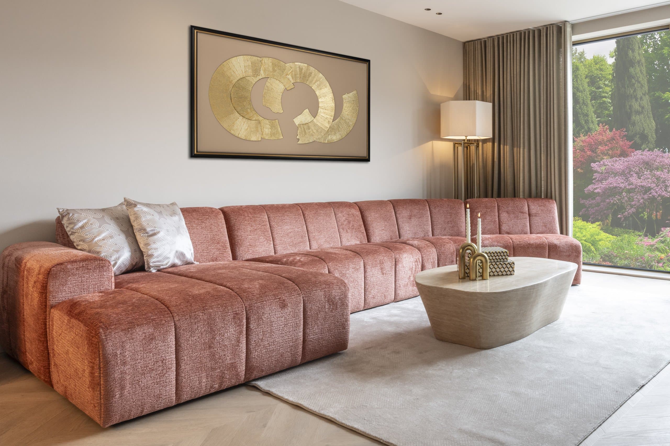 Breed wandpaneel met gouden cirkels in een donkere lijst aan een lichte muur in een woonkamer