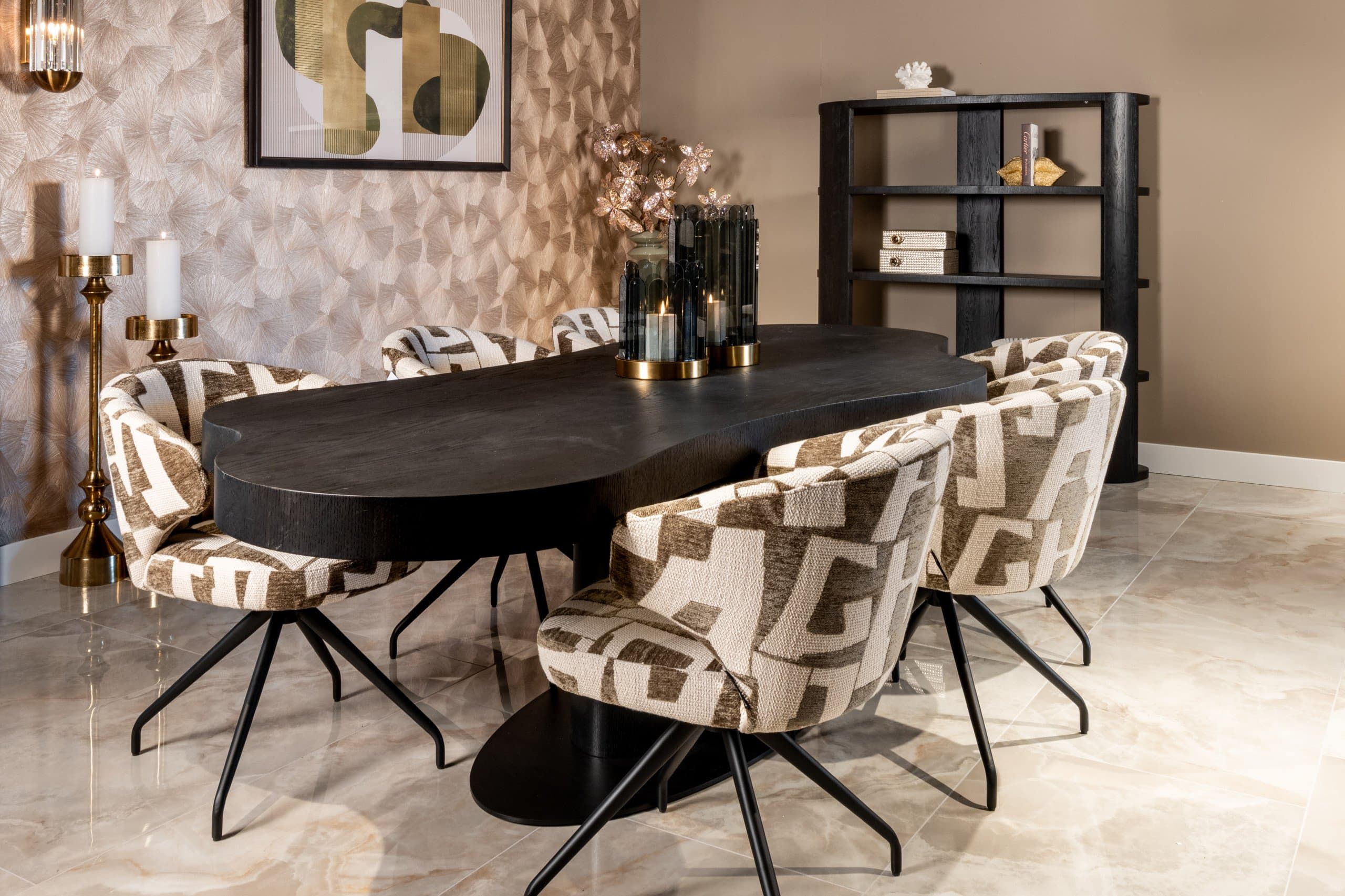 Eetkamer met een zwarte ovale eettafel, stoelen met grafische stof en een zwarte open kast, op een lichte vloer met marmertekening