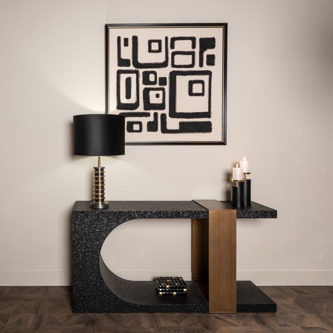 Zwarte consoletafel tegen een lichte wand met een tafellamp aan de linkerkant, kaarsen rechts en een grafisch schilderij erboven