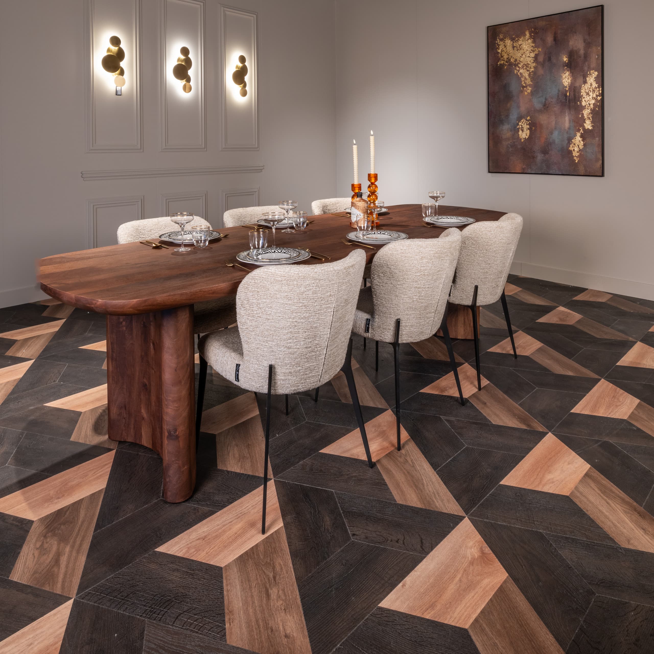 Gedekte houten eettafel met brandende kaarsen, glazen en bouclé stoelen in een ruimte met een donkere visgraatvloer.