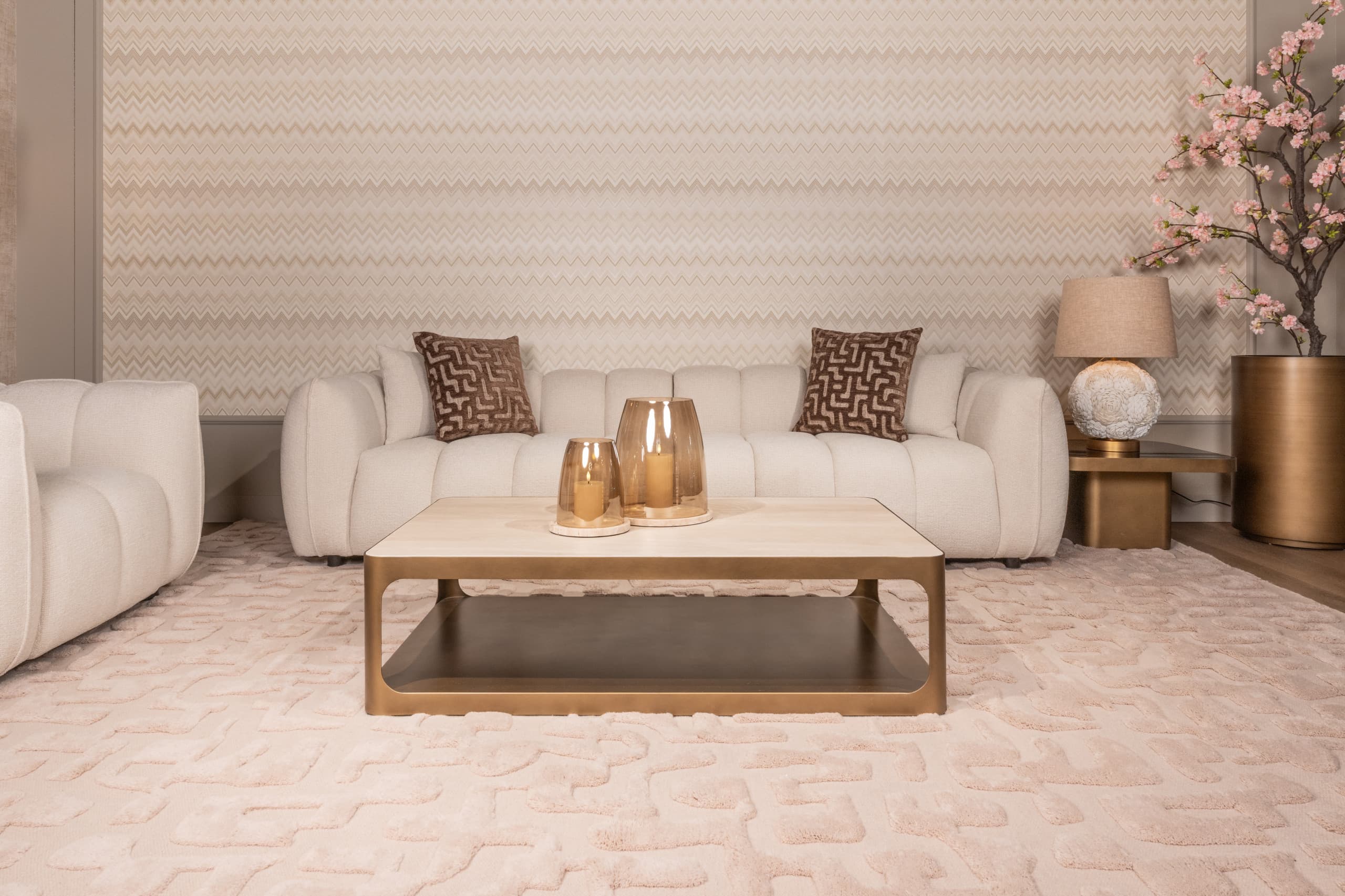 Lichte woonkamer met beige zitbanken, een brandende tafellamp op de bijzettafel en twee amberglazen windlichten op de salontafel